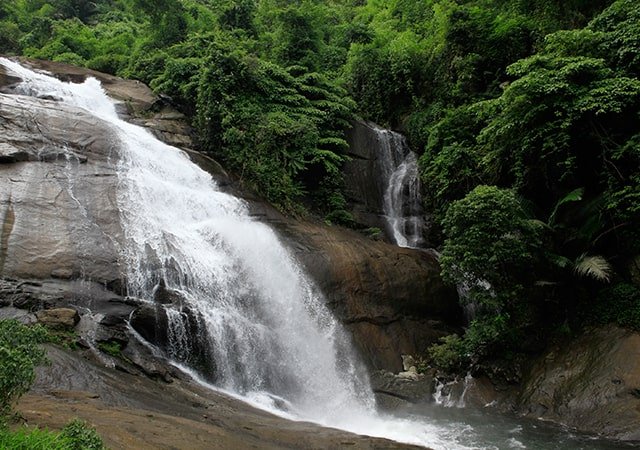 Thusharagiri Waterfalls cascading through lush green forest during monsoon season in Kerala